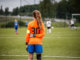 Girl goalkeeper looking at football pitch